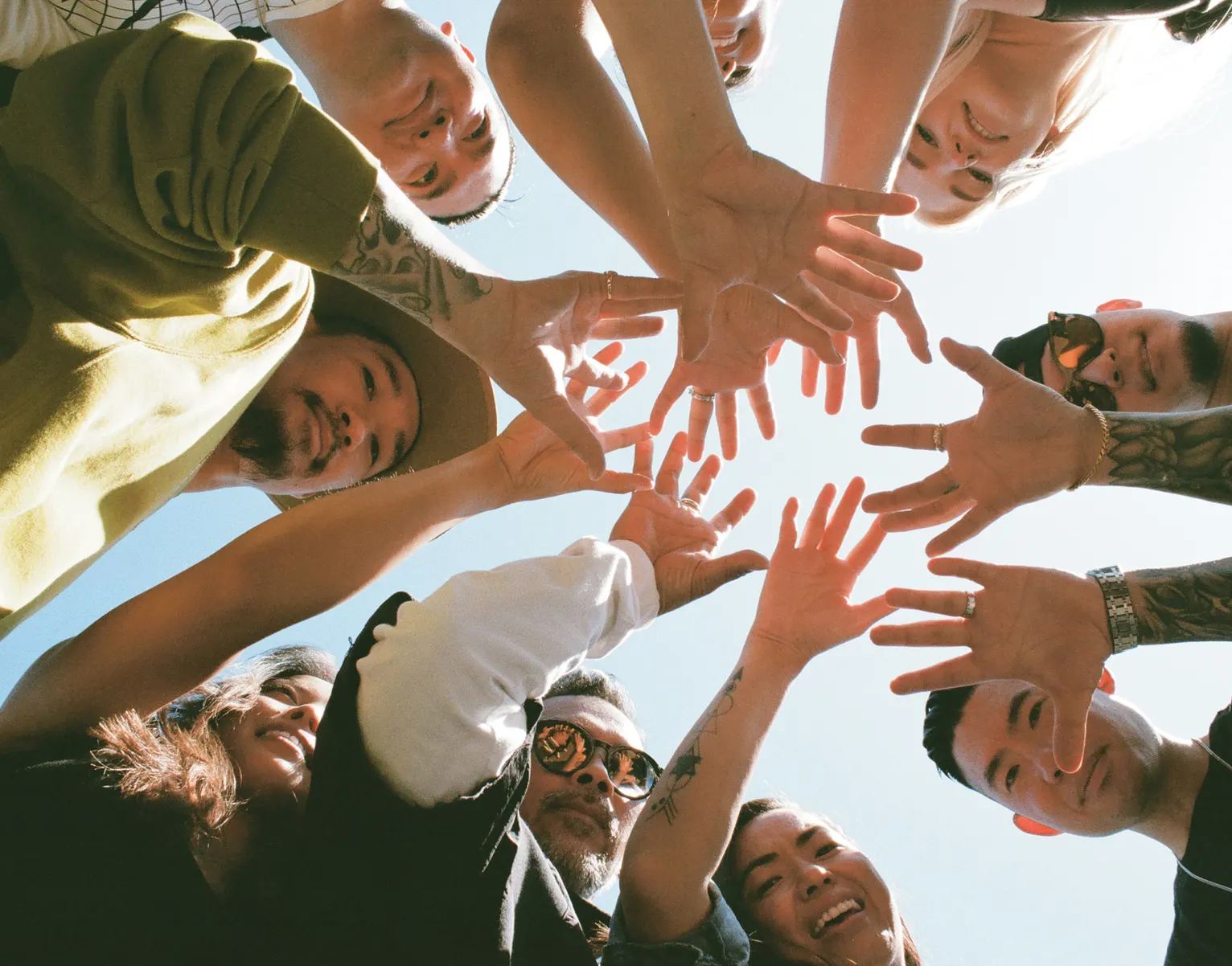 Hands meeting in the middle of a circle of crew members, shot from below